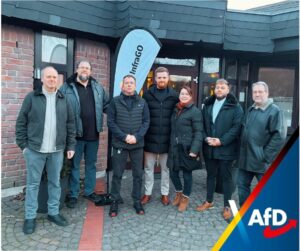 Sieben Personen stehen vor dem Bürgerhaus in Porta Westfalica neben einer Info-Fahne; am unteren Bildrand ist ein AfD-Logo eingeblendet.